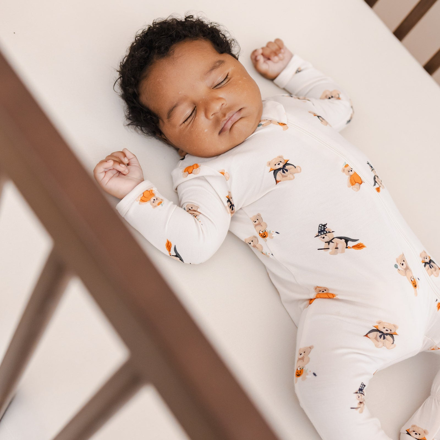 Baby in a Halloween teddy bear footie lying in a crib