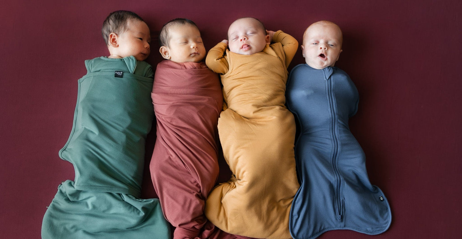 Four babies sleeping in sleep bags and swaddles in fall colours